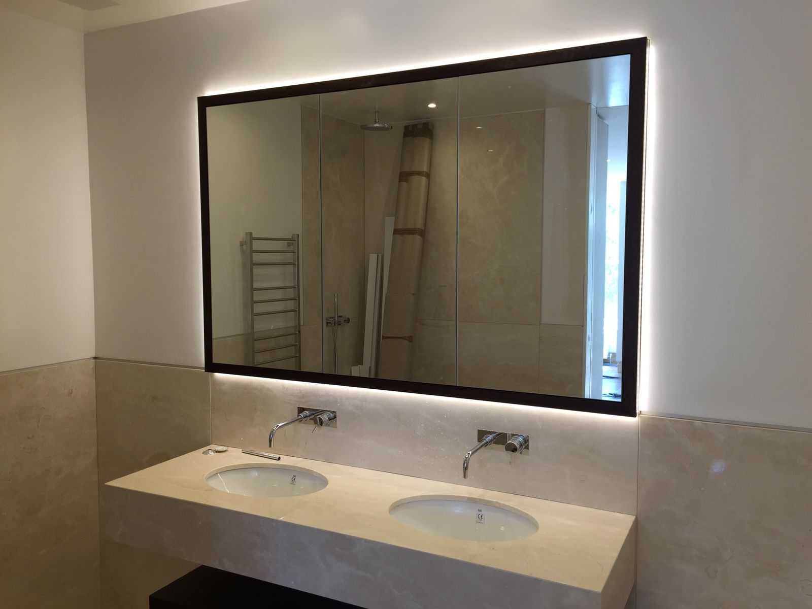 Backlit mirror cabinet over a marble double vanity