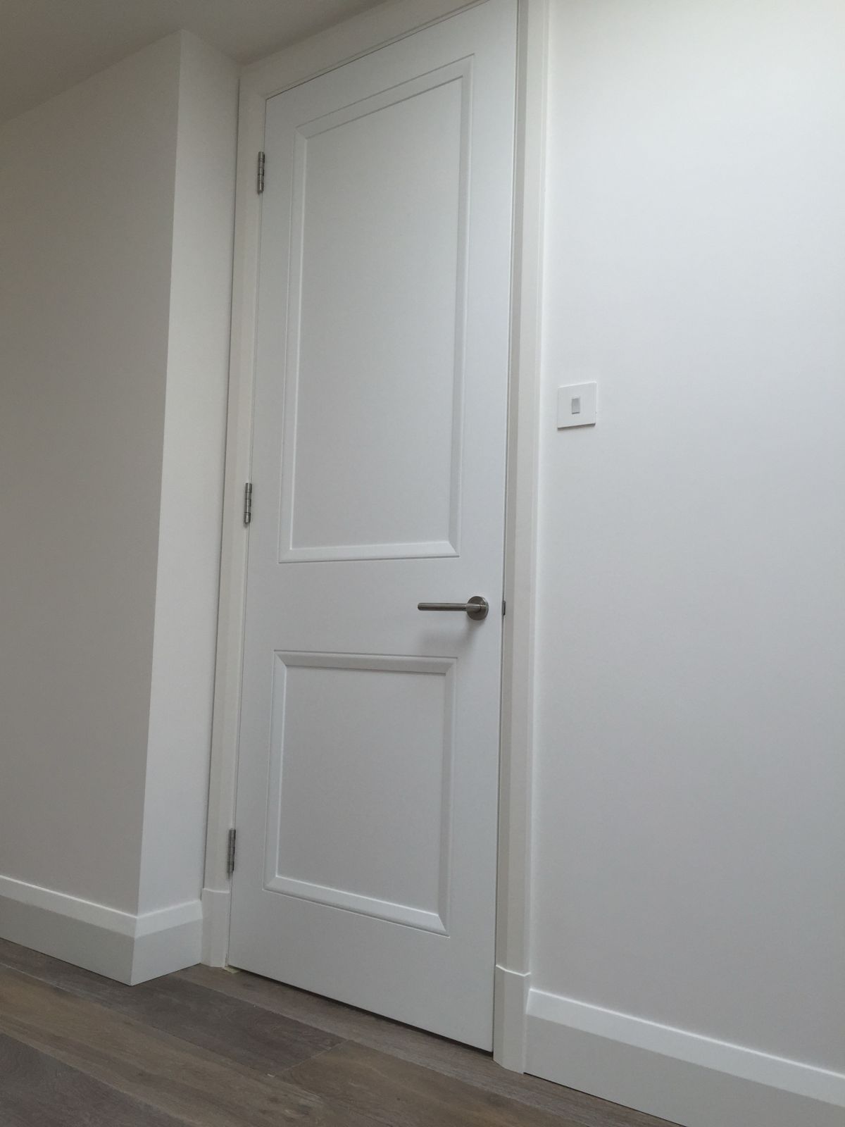 White two-panel internal door with lever handle and new skirting