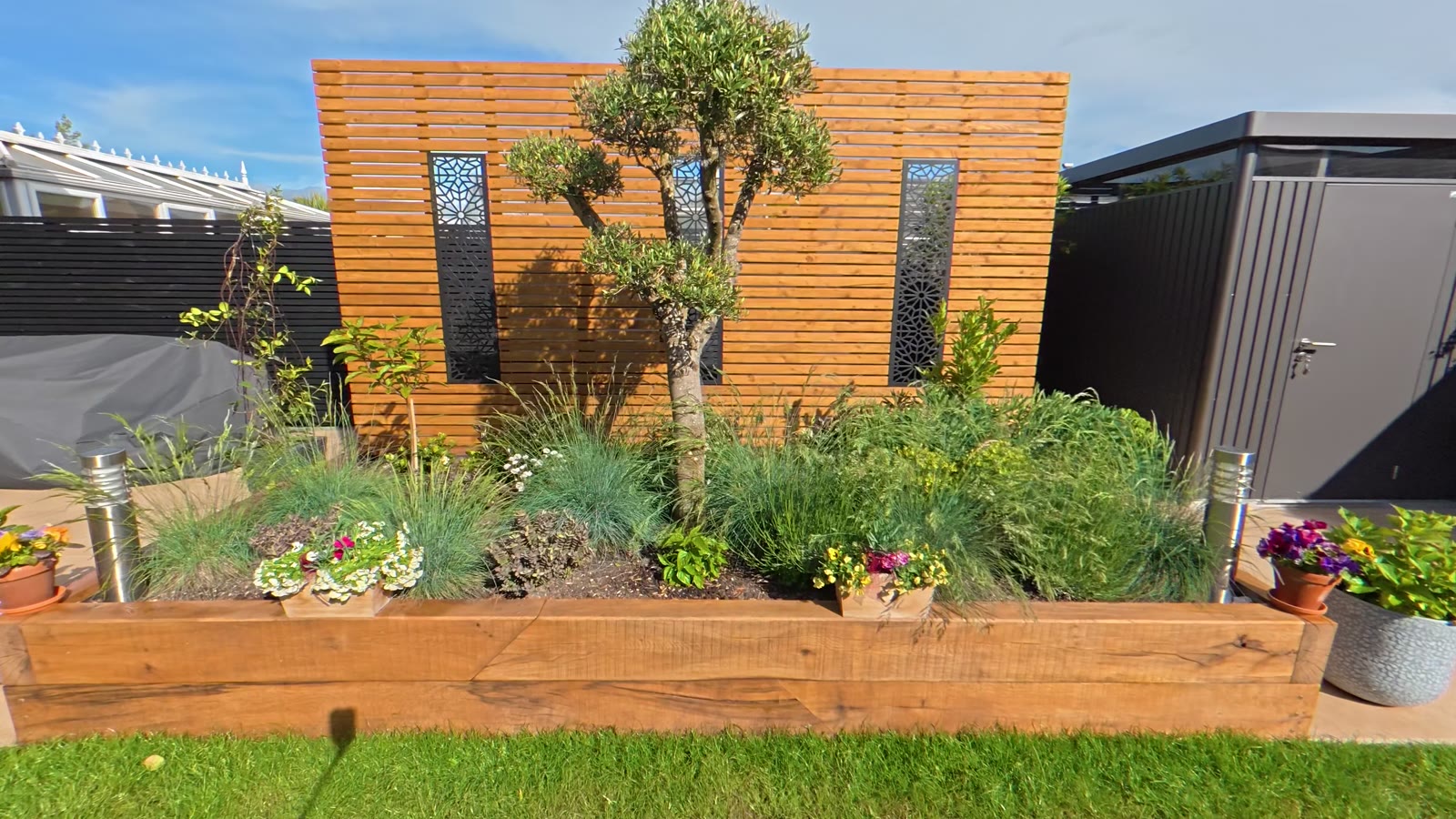 Slatted timber screen with decorative metal panels behind a raised sleeper bed