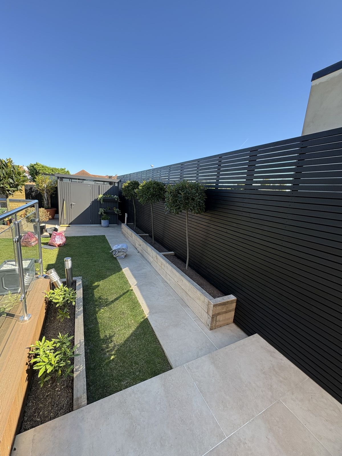 Garden with black slatted fence and porcelain path