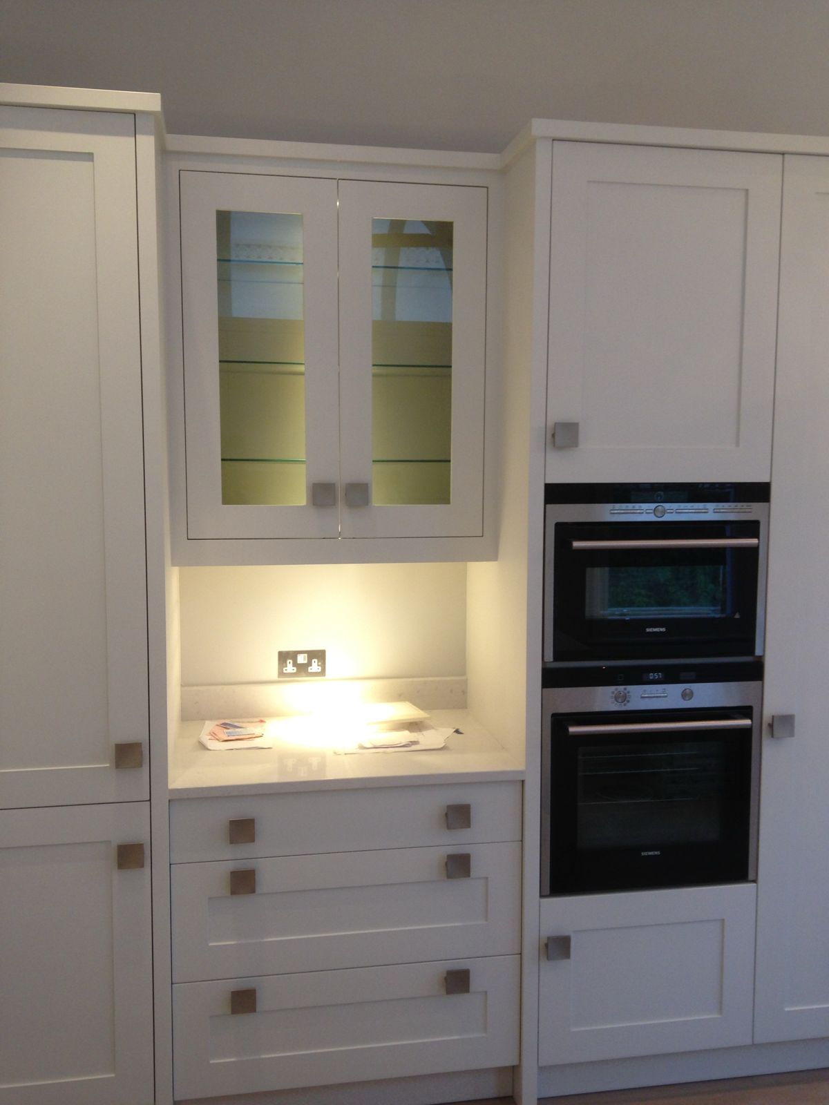 Shaker dresser unit with glazed doors beside built-in ovens