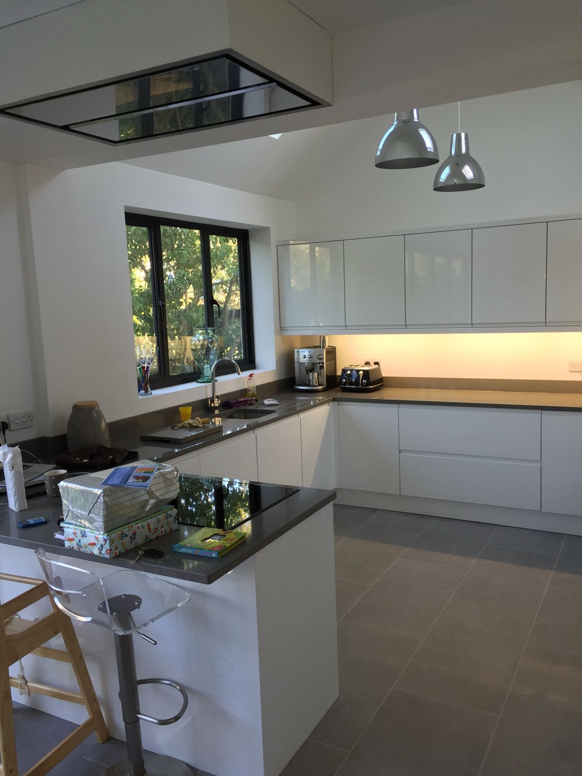 White gloss handleless kitchen with grey quartz worktops and ceiling extractor