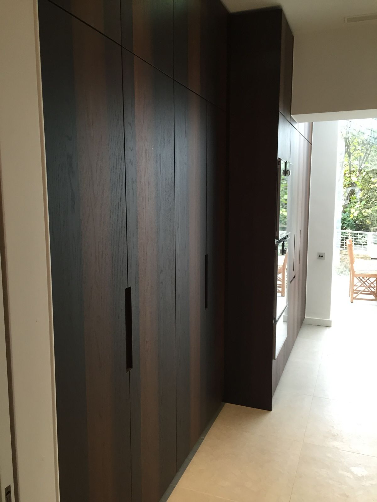 Floor-to-ceiling dark oak kitchen units with recessed handles
