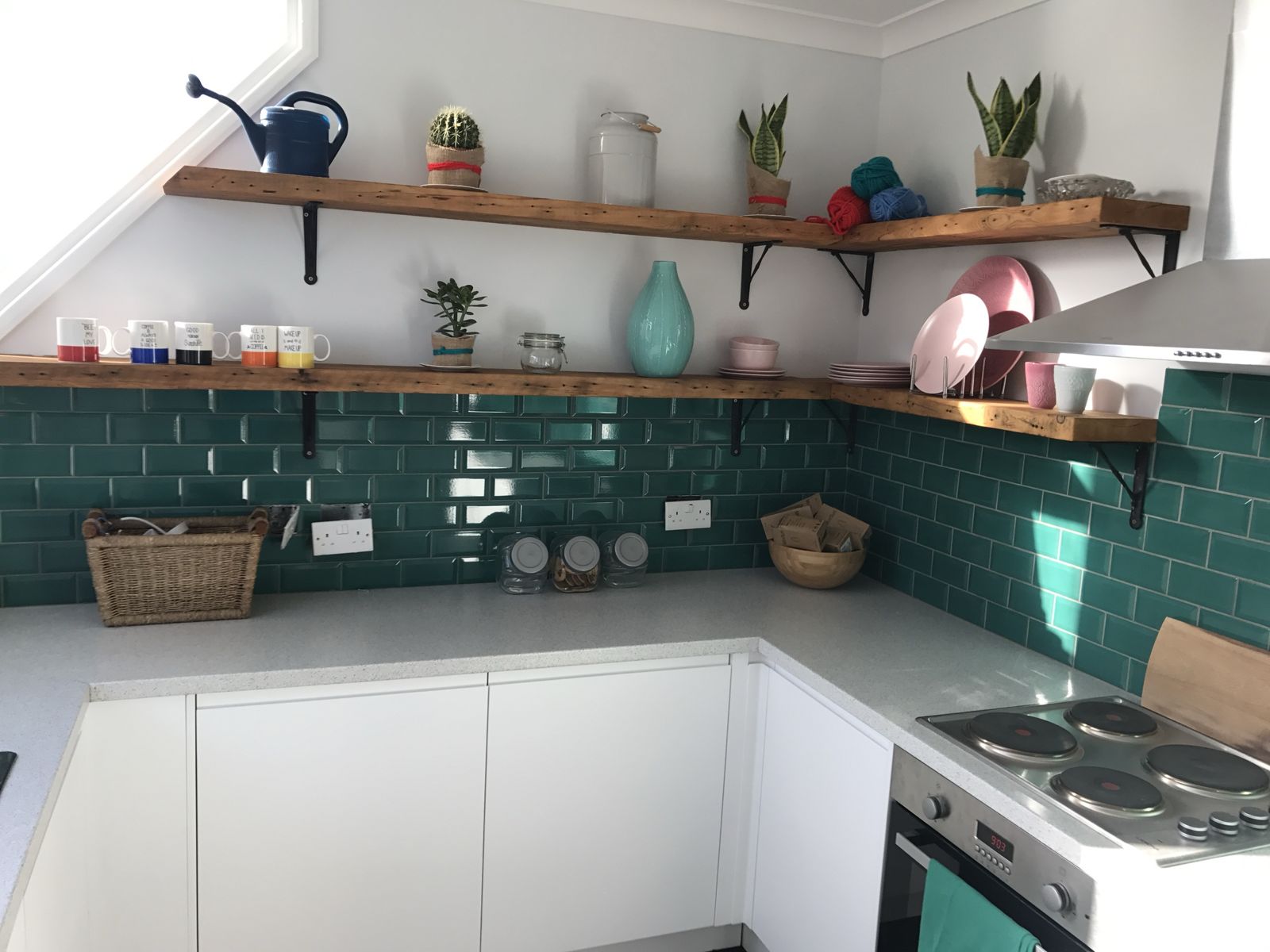 White kitchen with teal metro tiles and timber shelves