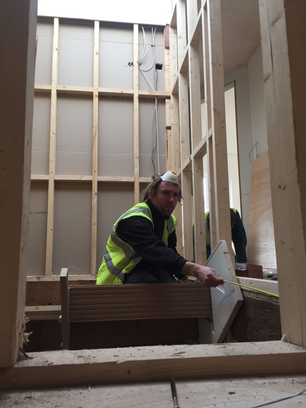 Maciej measuring on site inside a new timber stud frame