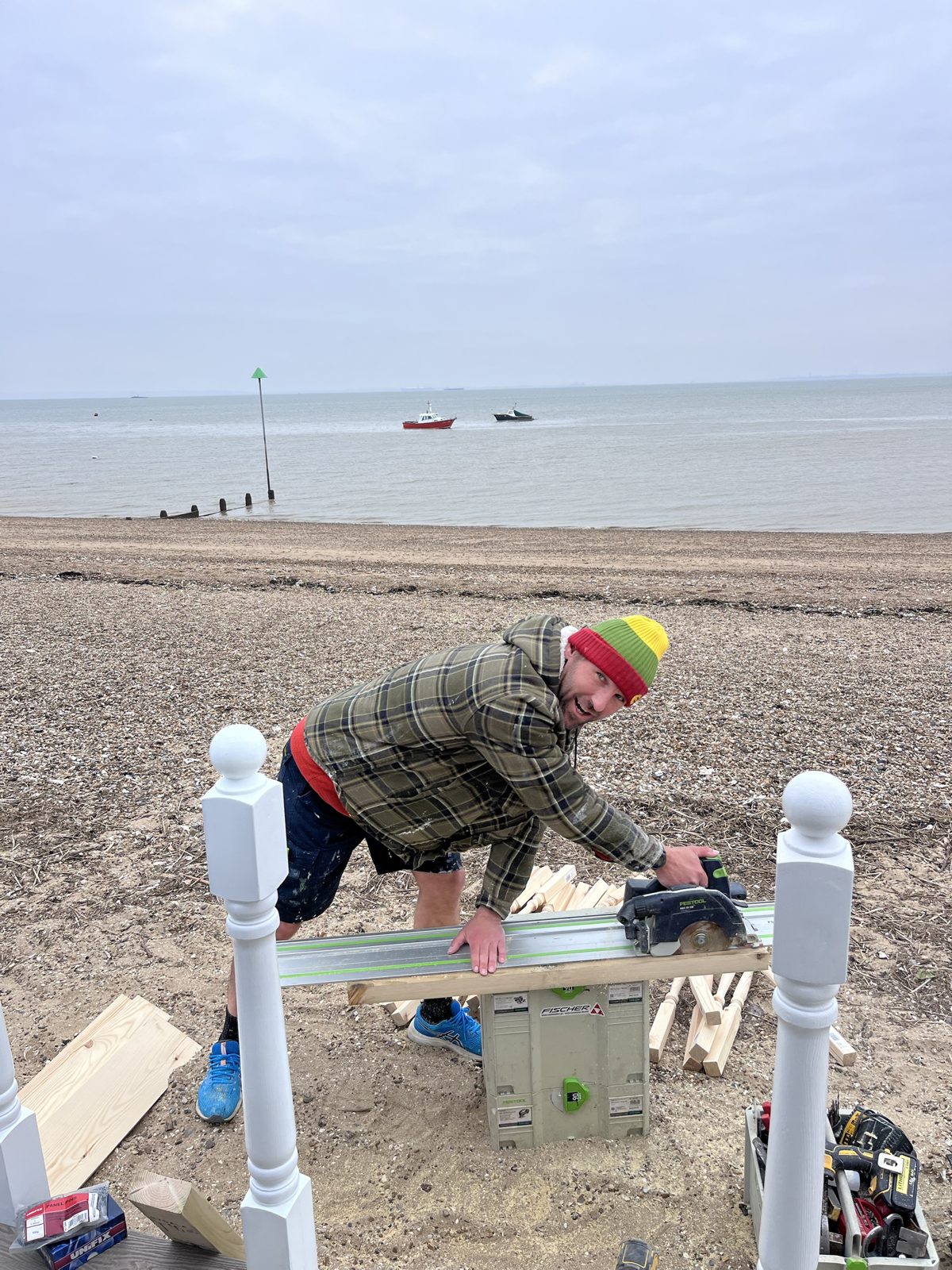 Maciej cutting timber with a track saw during a beach hut renovation on Southend seafront