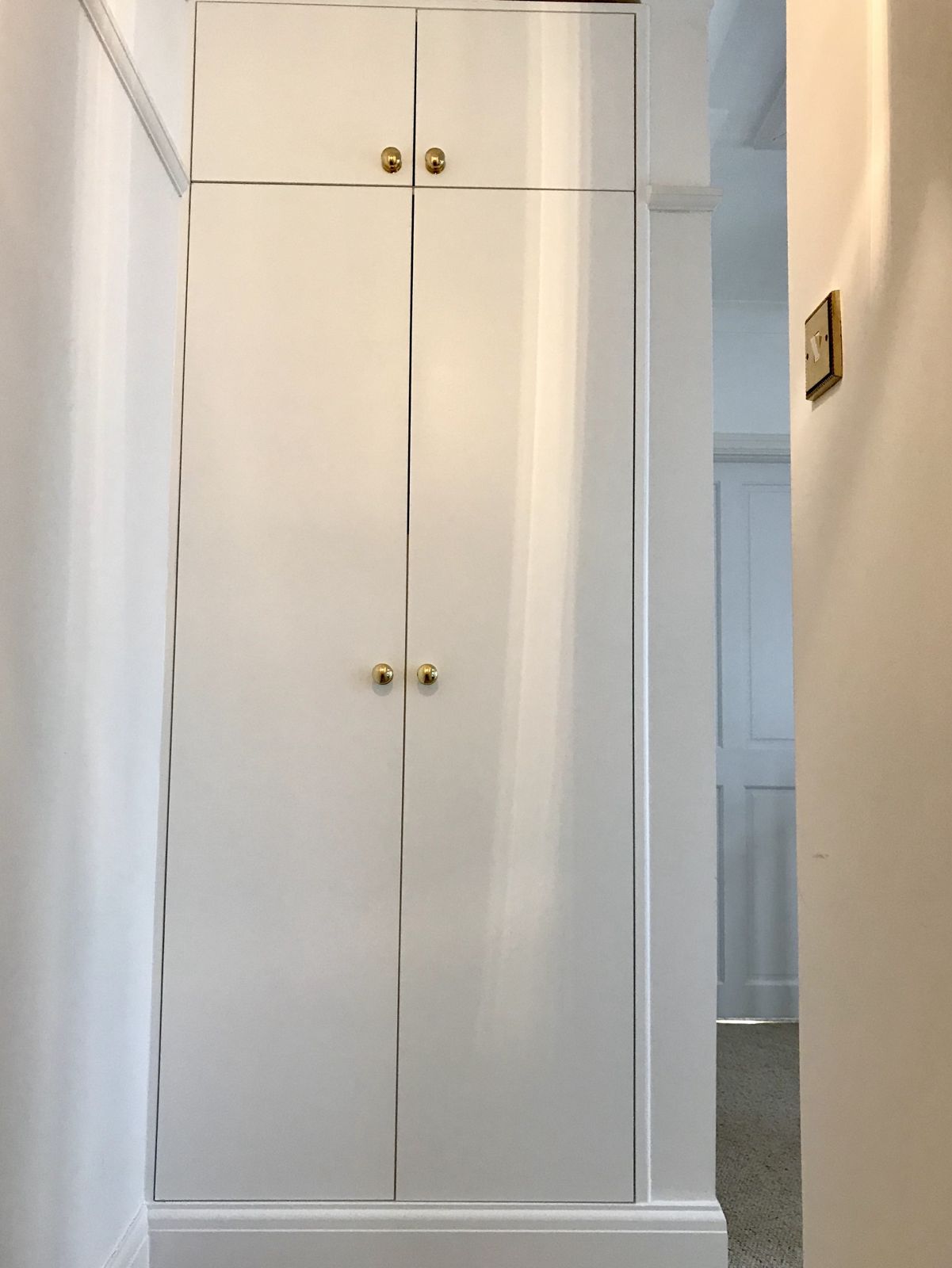 White alcove wardrobe with brass knobs