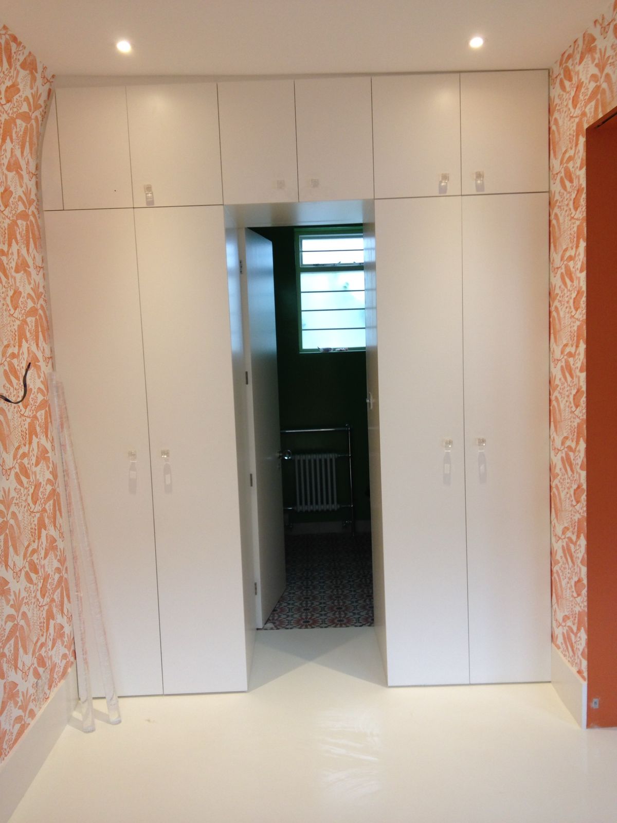 Floor-to-ceiling white wardrobes built around an en-suite door