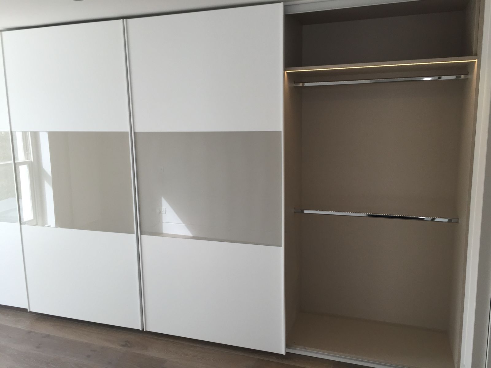 Sliding wardrobe doors with glass panels and a lit interior